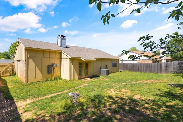 back of house with board and batten siding, a yard, french doors, and a fenced backyard