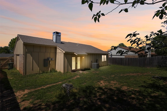 rear view of property with board and batten siding, a fenced backyard, french doors, and central air condition unit