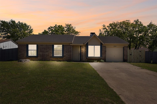 ranch-style home with brick siding, an attached garage, driveway, and a front lawn