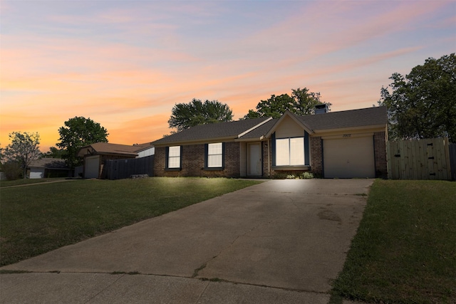 ranch-style house with fence, concrete driveway, an attached garage, brick siding, and a front yard