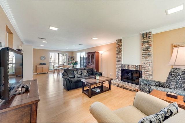 living area with crown molding, visible vents, a brick fireplace, and light wood-style floors