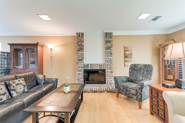 living room featuring crown molding, visible vents, light wood finished floors, and a fireplace