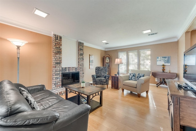 living room featuring visible vents, light wood-type flooring, crown molding, and a brick fireplace