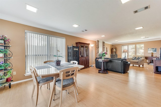 dining area featuring light wood-style flooring, crown molding, baseboards, and visible vents