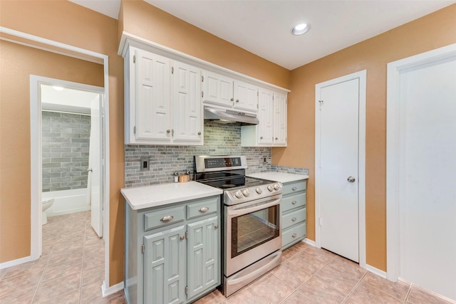 kitchen featuring white cabinets, under cabinet range hood, light countertops, stainless steel electric range, and decorative backsplash