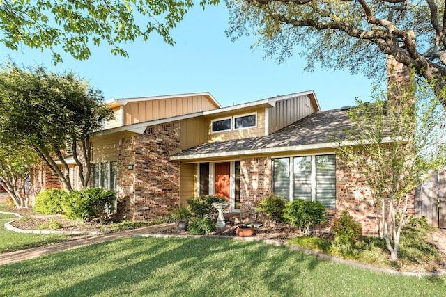 view of front facade with a front yard, brick siding, and board and batten siding