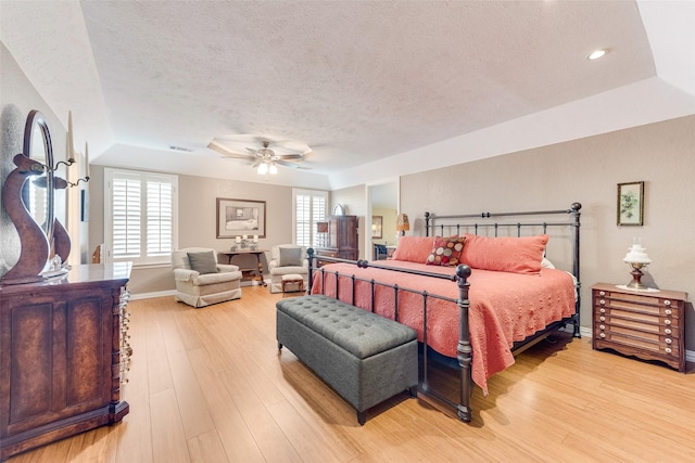 bedroom with visible vents, baseboards, a ceiling fan, light wood-style floors, and a textured ceiling