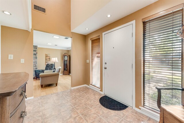 foyer entrance with a wealth of natural light, light tile patterned floors, visible vents, and baseboards