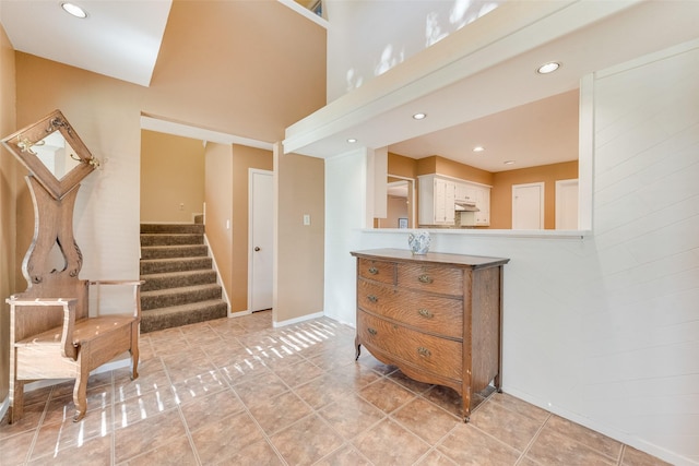 interior space featuring a high ceiling, baseboards, tile patterned flooring, and recessed lighting