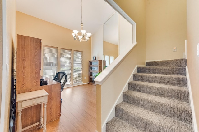 staircase featuring baseboards, an inviting chandelier, and hardwood / wood-style flooring