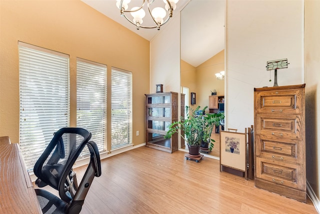 office space featuring light wood-style flooring, high vaulted ceiling, an inviting chandelier, and baseboards