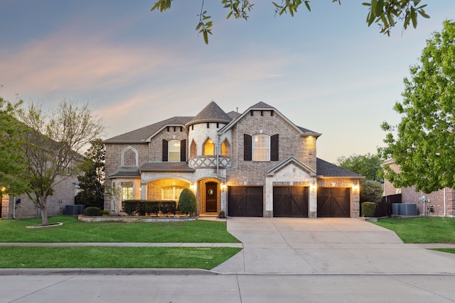 french country style house featuring concrete driveway, stone siding, brick siding, fence, and a lawn