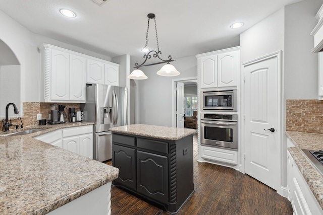 kitchen with arched walkways, a sink, white cabinets, and stainless steel appliances
