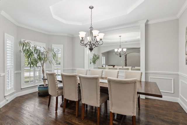 dining room featuring dark wood-type flooring, a tray ceiling, ornamental molding, and an inviting chandelier