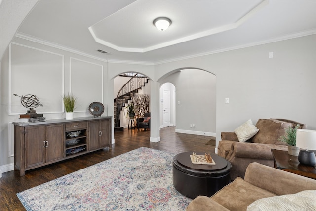 living area with arched walkways, visible vents, stairway, a raised ceiling, and dark wood-style floors