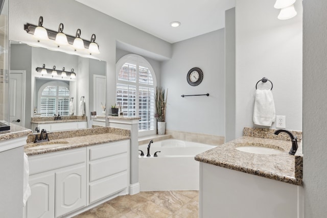 full bathroom with a sink, two vanities, and a bath