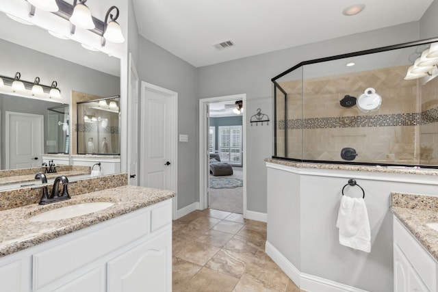 full bath with two vanities, baseboards, a stall shower, visible vents, and a sink