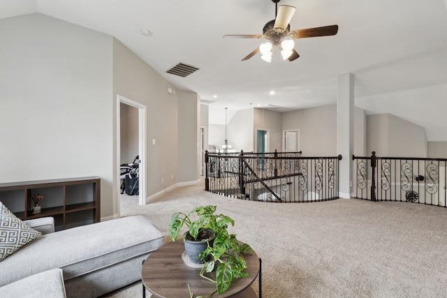 carpeted living area featuring ceiling fan with notable chandelier, baseboards, vaulted ceiling, and visible vents