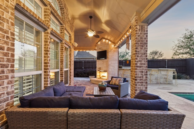 view of patio / terrace featuring a fenced backyard, an outdoor living space with a fireplace, and a ceiling fan