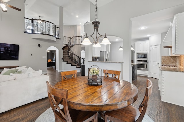 dining room featuring ceiling fan, dark wood-type flooring, arched walkways, recessed lighting, and stairs