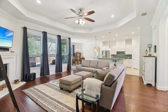 living room with ceiling fan, a raised ceiling, dark wood-type flooring, visible vents, and recessed lighting