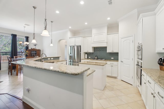 kitchen with stainless steel fridge, visible vents, crown molding, and a large island with sink