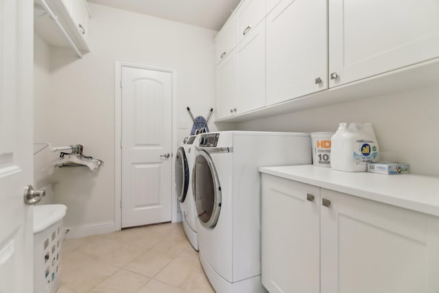laundry area featuring separate washer and dryer, baseboards, cabinet space, and light tile patterned floors