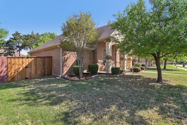 view of front of house with a front lawn, brick siding, and roof with shingles