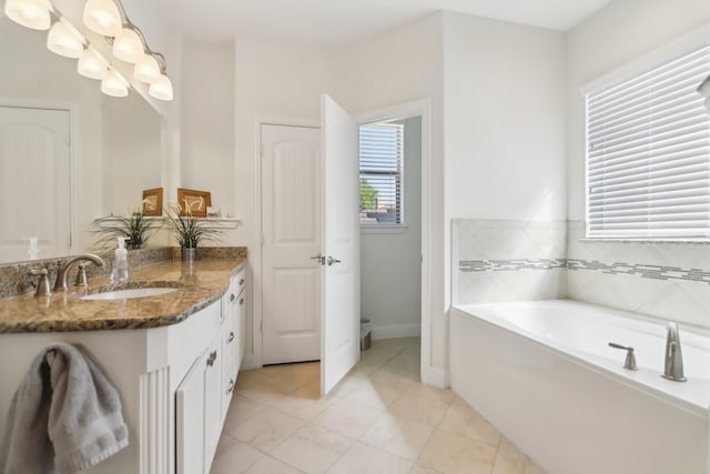 bathroom with baseboards, a garden tub, tile patterned floors, and vanity