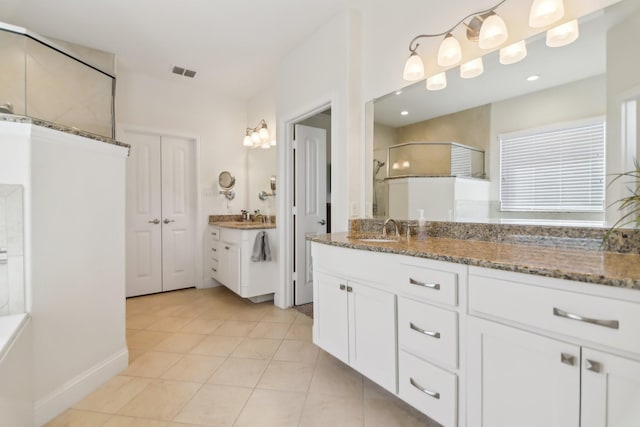 bathroom with vanity, walk in shower, baseboards, tile patterned flooring, and visible vents