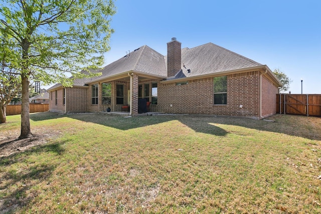 rear view of property featuring brick siding, a yard, roof with shingles, and a fenced backyard