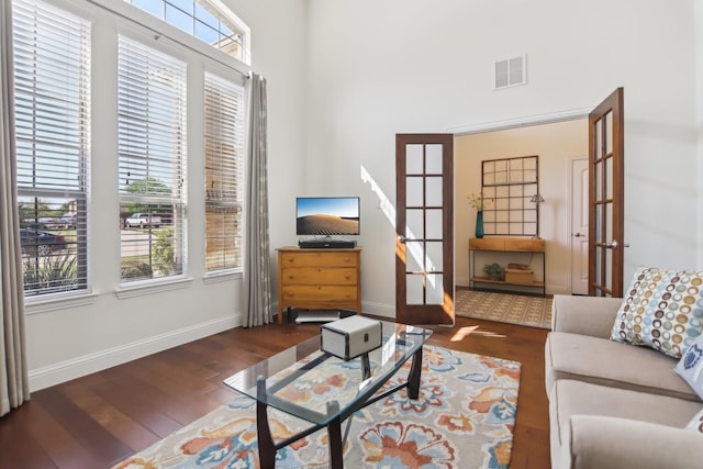 living area with wood finished floors, visible vents, a healthy amount of sunlight, and french doors