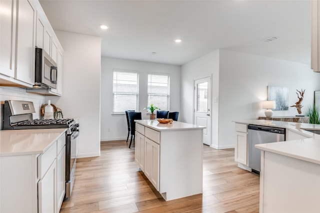 kitchen featuring light wood-type flooring, stainless steel appliances, light countertops, and a center island