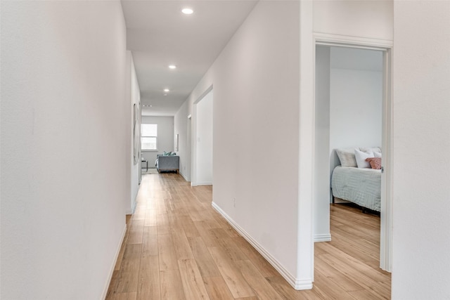 corridor featuring light wood-style floors, recessed lighting, and baseboards