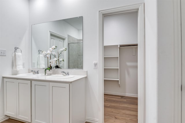 1005 Manuel Dr, Fate, TX 75087 - bathroom featuring a tile shower, double vanity, wood finished floors, and a spacious closet