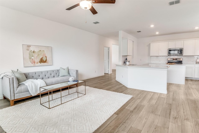 living room with visible vents, ceiling fan, recessed lighting, and light wood-style flooring