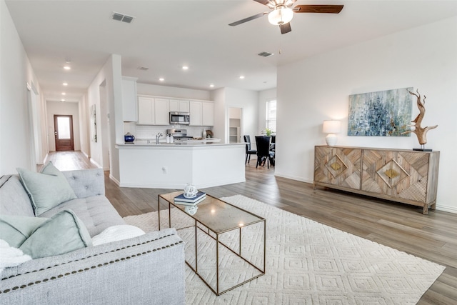 living room with visible vents, a ceiling fan, and light wood finished floors