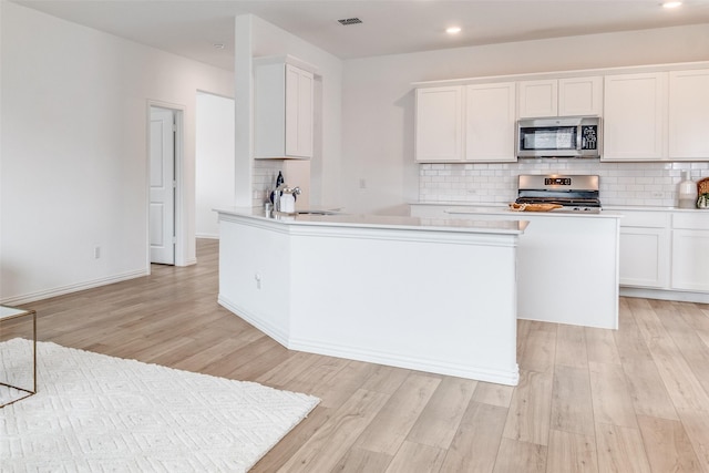 kitchen with white cabinets, visible vents, appliances with stainless steel finishes, and decorative backsplash