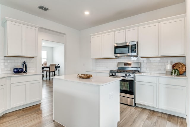 kitchen with stainless steel appliances, a center island, visible vents, backsplash, and light countertops