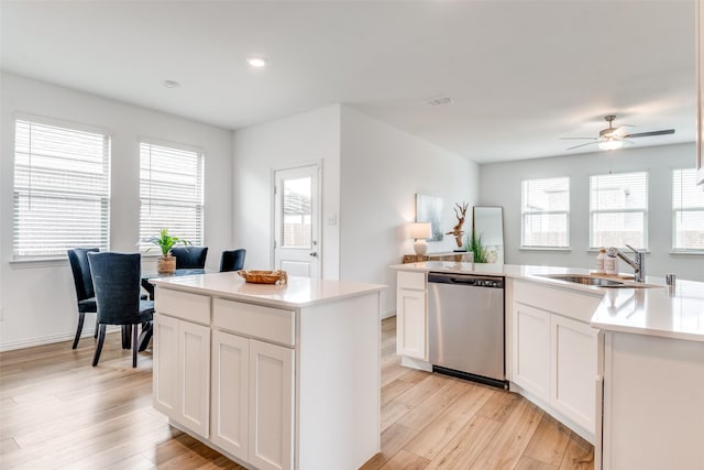 kitchen with light wood-style flooring, a sink, a healthy amount of sunlight, a kitchen island, and dishwasher