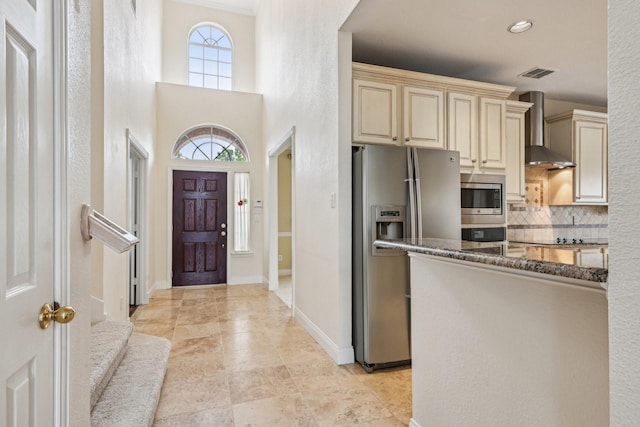 604 Nelson Ct, Plano, TX 75025 - kitchen with backsplash, appliances with stainless steel finishes, cream cabinets, dark stone counters, and wall chimney exhaust hood