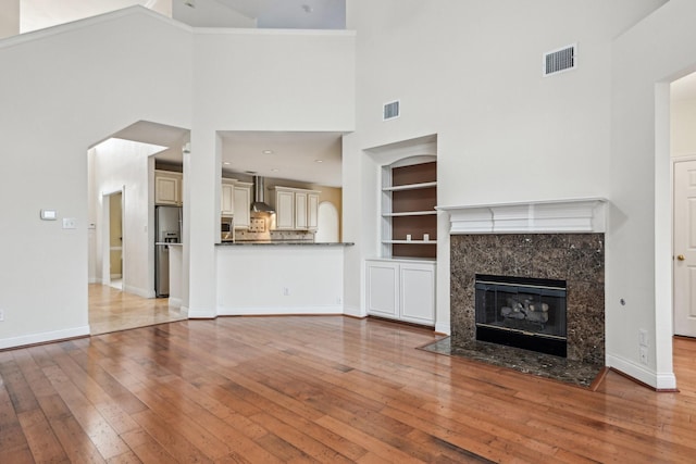 604 Nelson Ct, Plano, TX 75025 - unfurnished living room with a premium fireplace, a high ceiling, visible vents, and hardwood / wood-style flooring