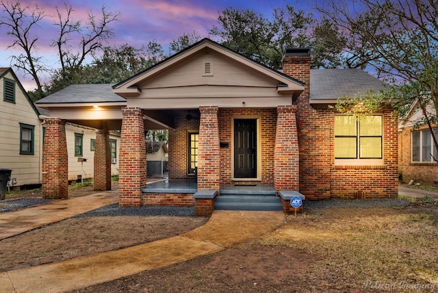 bungalow-style house featuring a chimney and brick siding