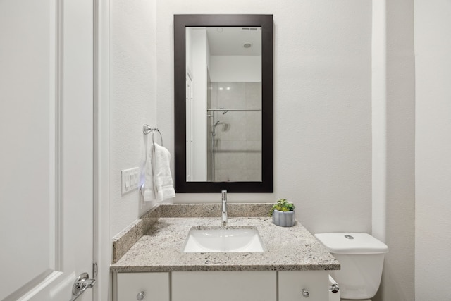 bathroom with toilet, a textured wall, and vanity