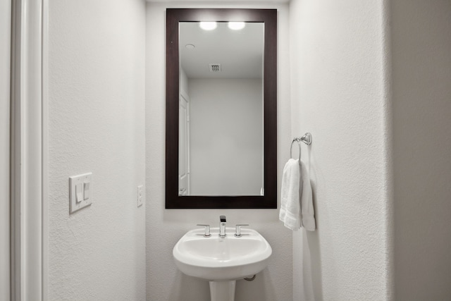 bathroom with a textured wall, visible vents, and a sink