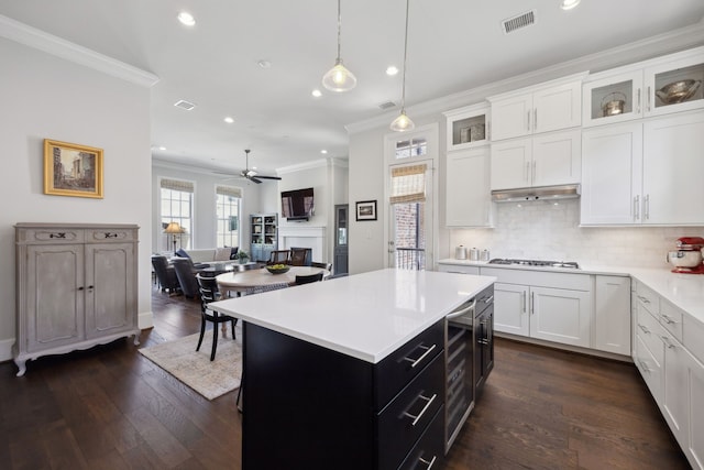 kitchen with crown molding, ceiling fan, light countertops, white cabinetry, and backsplash