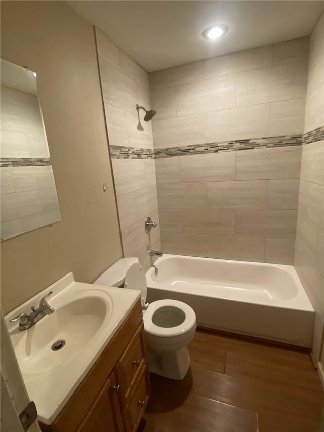 bathroom featuring toilet, vanity, wood finished floors, and  shower combination