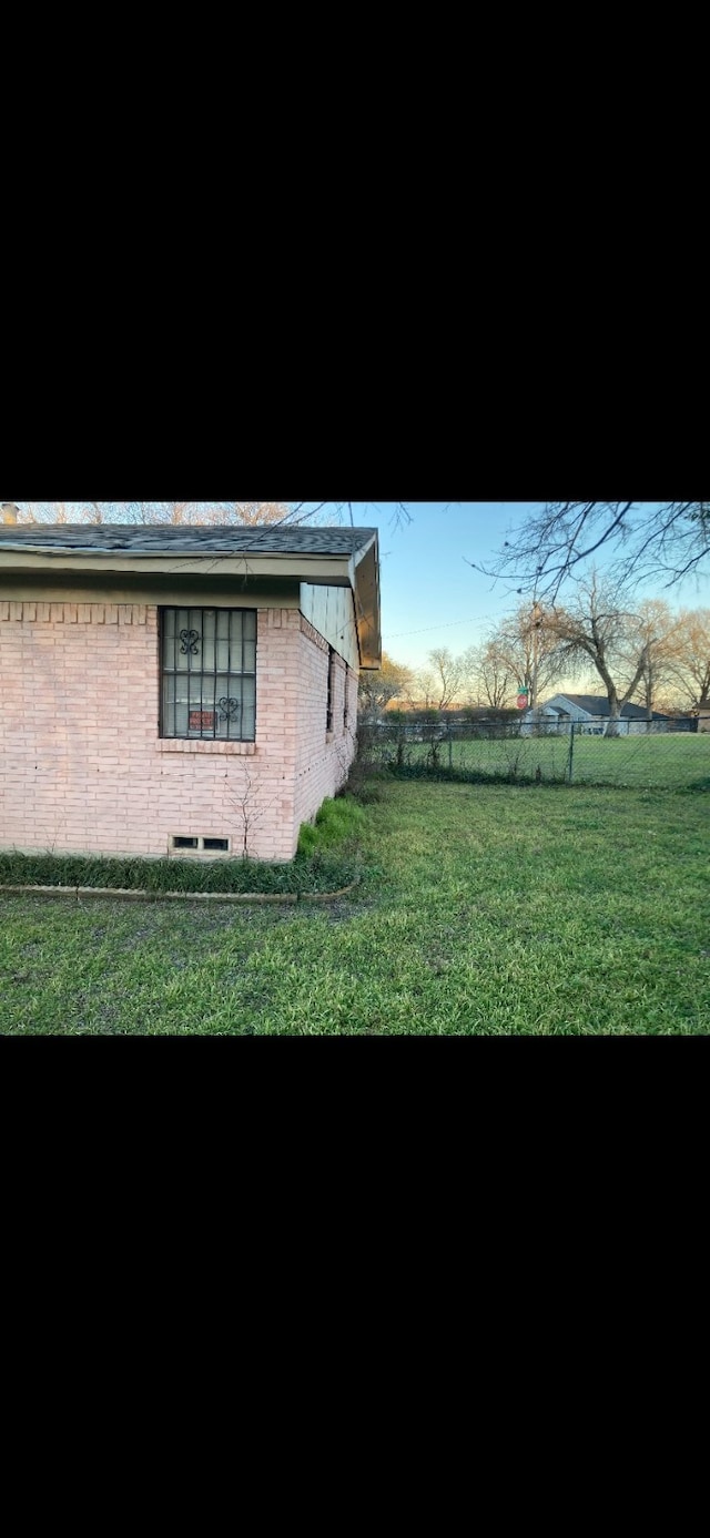 view of property exterior featuring brick siding and a lawn
