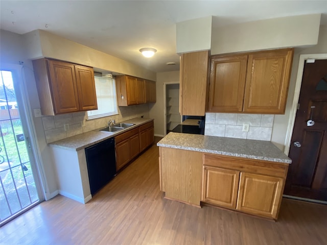 kitchen with a sink, decorative backsplash, light wood-type flooring, and dishwasher
