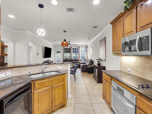 kitchen with dark stone countertops, visible vents, a sink, appliances with stainless steel finishes, and brown cabinetry